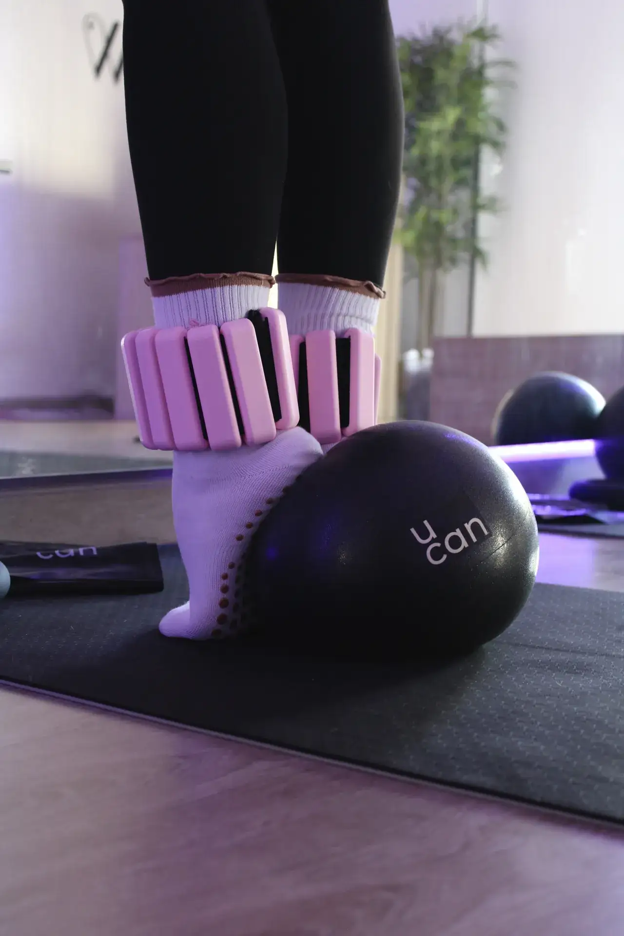 Tobilleras rosas y pelota de pilates sobre el tapete